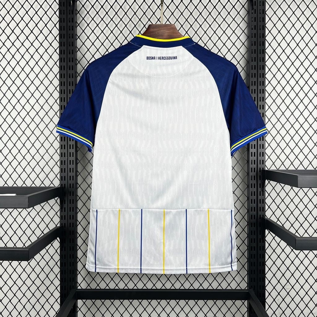 Leazofoot BOSNIE 2026 away jersey, white with blue sleeves and yellow/blue striped hem. Features "BOSNA I HERCEGOVINA" text.