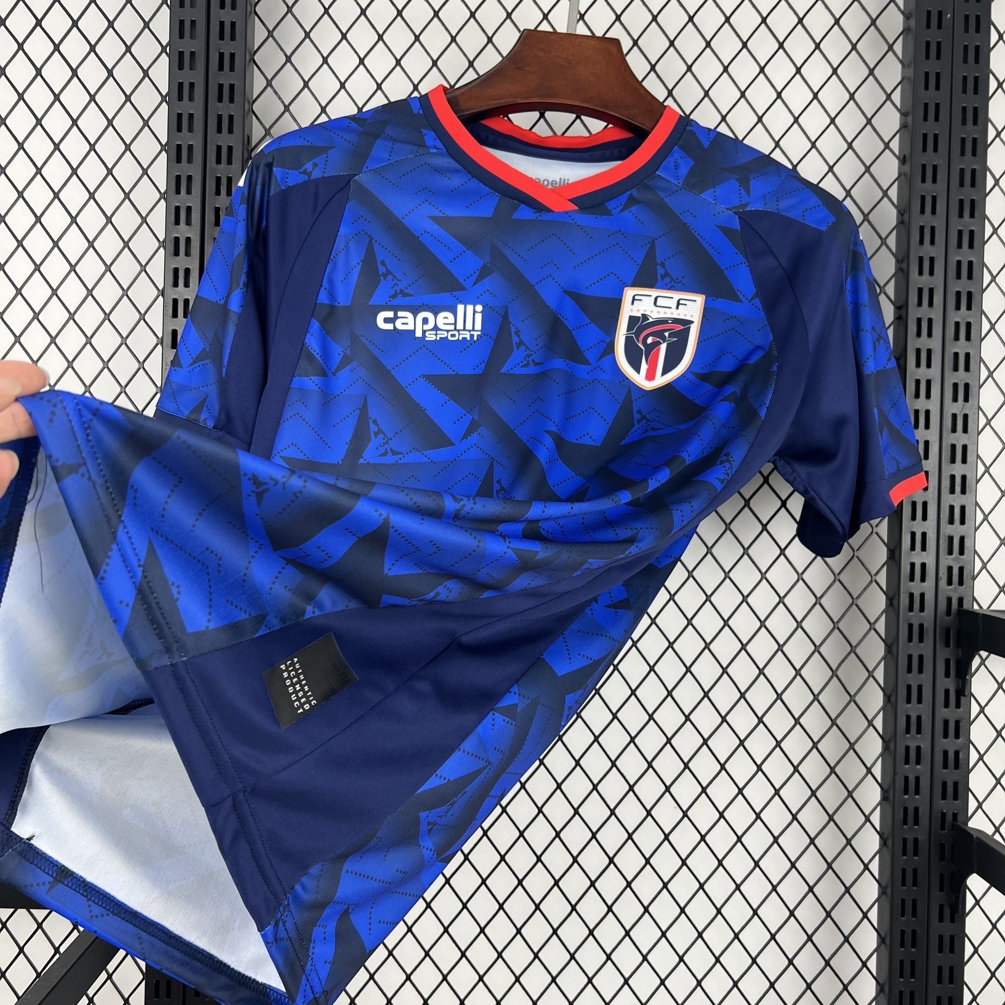 Leazofoot CAP-VERT home jersey 2026, blue with black geometric pattern and red trim.