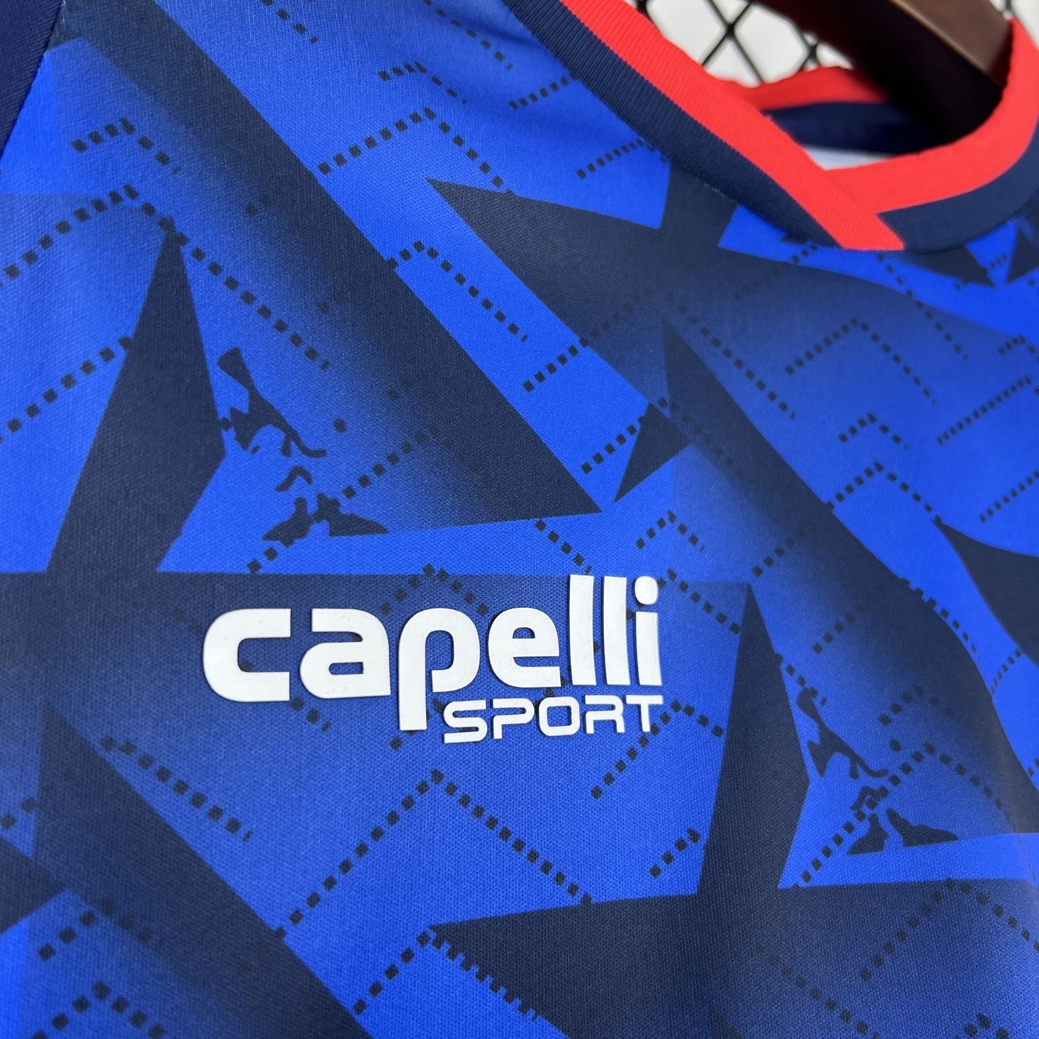 Leazofoot CAP-VERT home jersey 2026, blue with dark blue star pattern and red collar trim.
