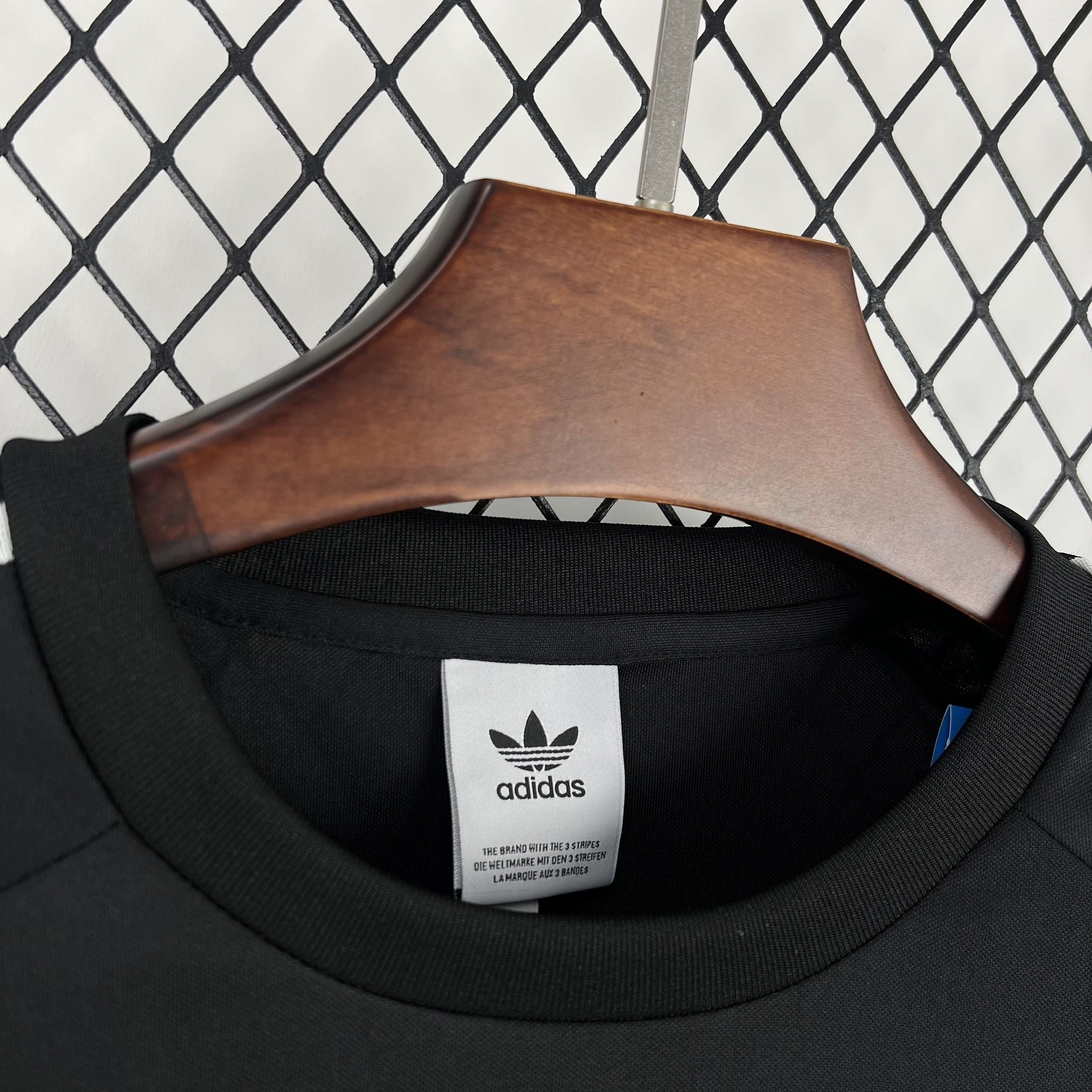 Leazofoot CHILI 2026 concept soccer jersey in black with adidas trefoil logo tag on a wooden hanger