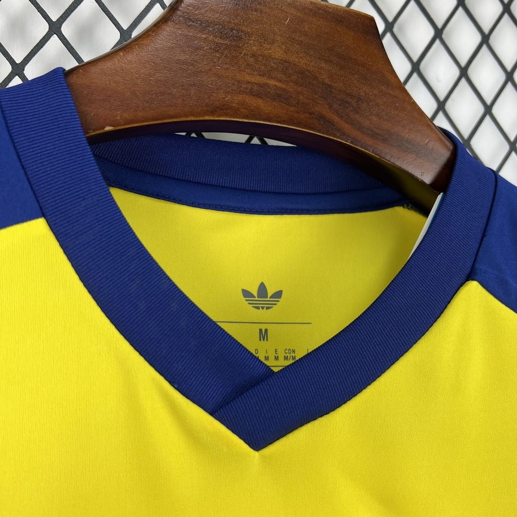 Leazofoot Colombia 2026 pre-match soccer jersey in yellow with blue V-neck collar and Adidas trefoil logo.