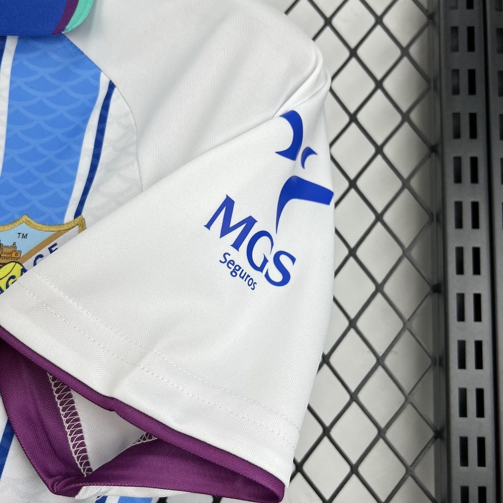 Leazofoot Malaga 26/27 home football jersey featuring white fabric, blue stripes, and MGS Seguros sleeve sponsor logo.