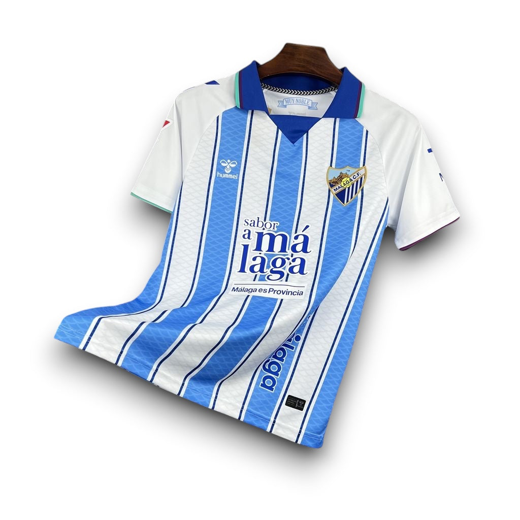 Leazofoot Malaga CF 26/27 home jersey with blue and white vertical stripes, polo collar, and team crest.