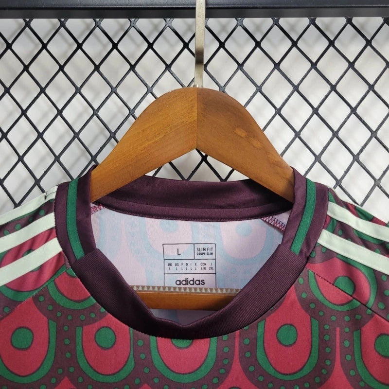 Leazofoot Mexico 2024 home soccer jersey with maroon and green geometric pattern and slim fit design on a hanger.