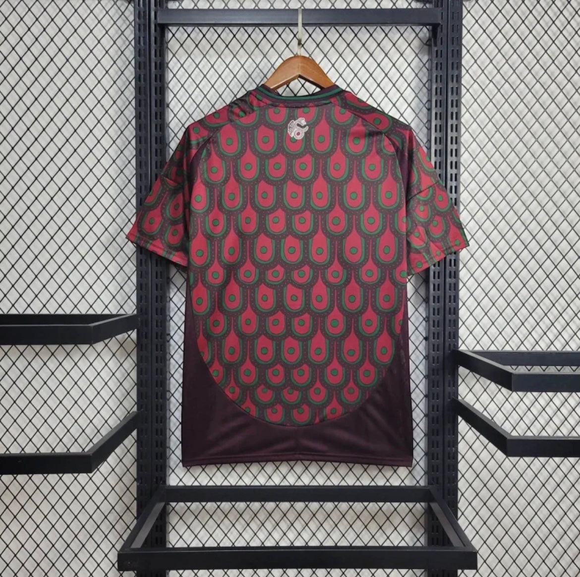 Leazofoot Mexico 2024 home soccer jersey featuring a maroon and green scale pattern on a hanger.