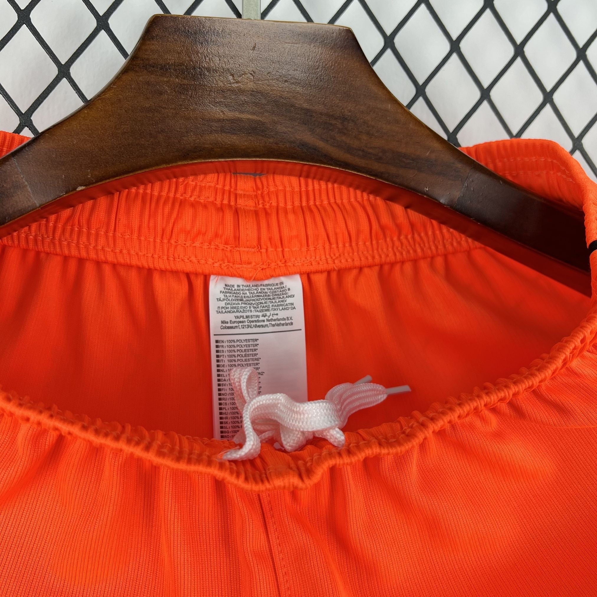 Leazofoot orange polyester shorts with drawstring waist and care label detail.