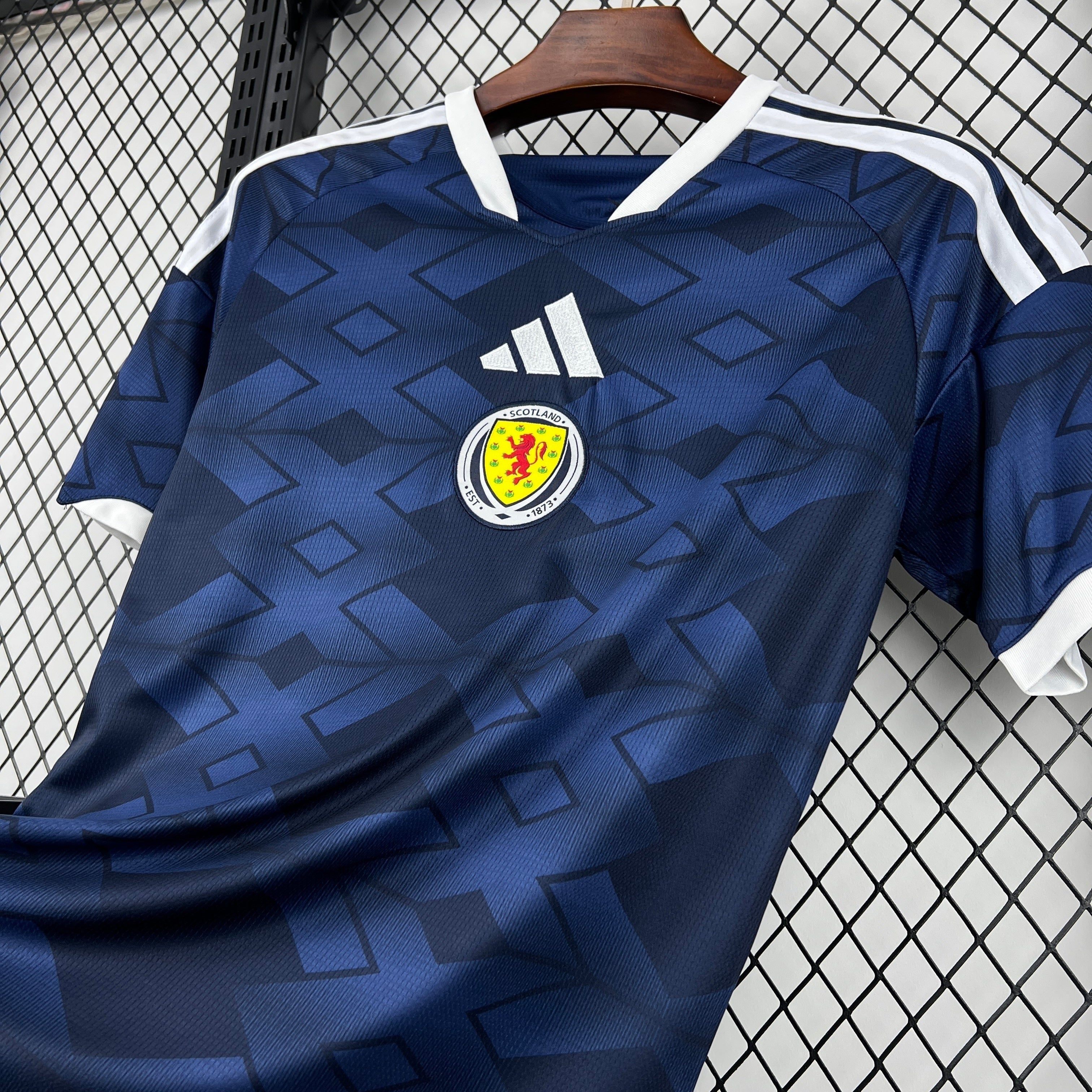 Leazofoot Scotland home jersey 2026, dark blue with geometric pattern, white collar and sleeve trim.