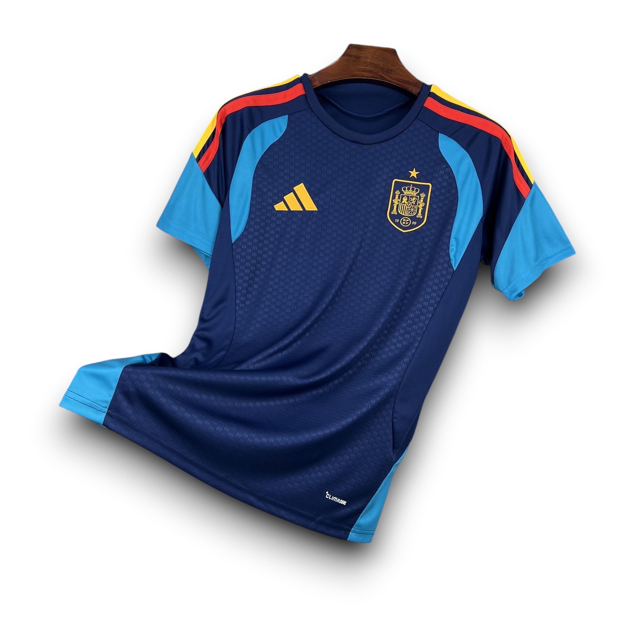 Leazofoot Spain 2026 pre-match football jersey in navy blue with light blue sleeves and red/yellow accents on the shoulders.