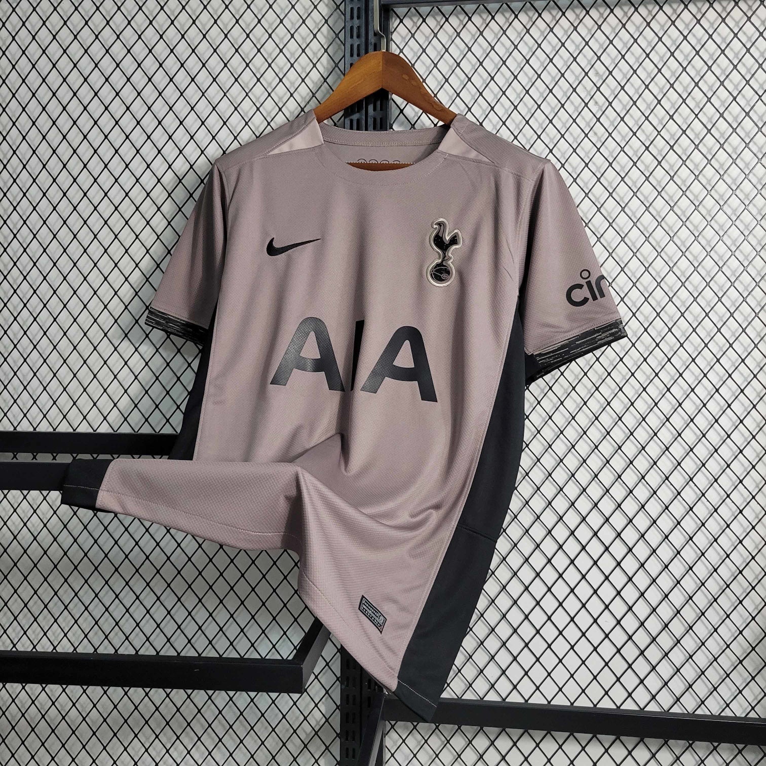Leazofoot Tottenham 23/24 third kit jersey. Taupe with black accents, AIA logo, Nike swoosh, and club crest.