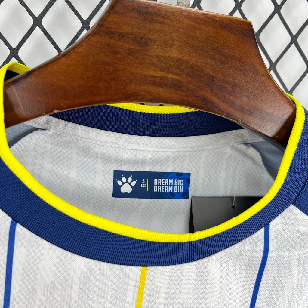 Leazofoot white football jersey with blue and yellow trim, featuring a subtle geometric pattern and vertical stripes.