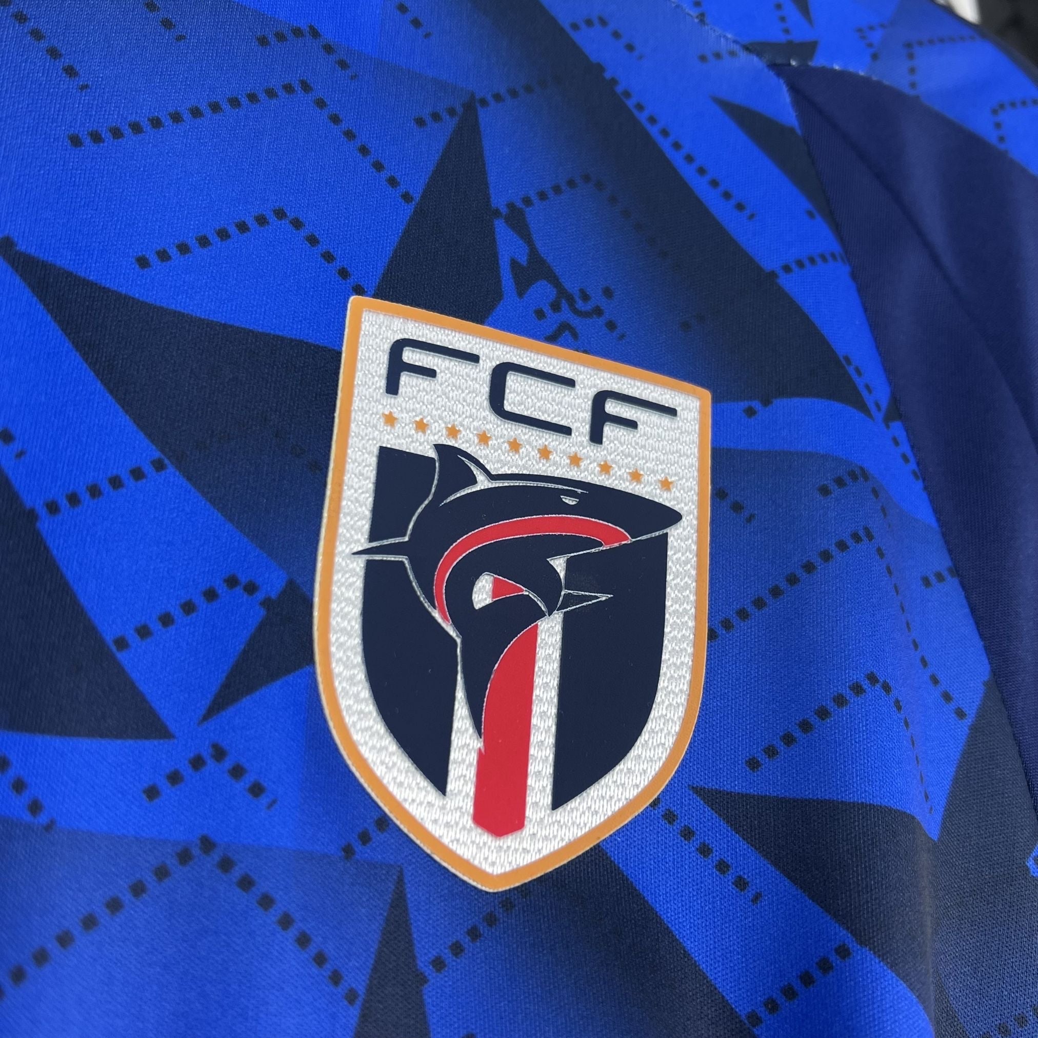 Leazofoot CAP-VERT - MAILLOT DOMICILE 2026 blue jersey with a shark emblem and geometric pattern.