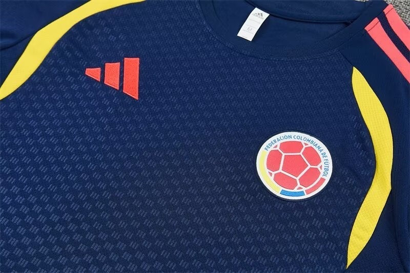Leazofoot Colombia 2026 training jersey in navy blue with yellow side panels, red logo, and team crest.