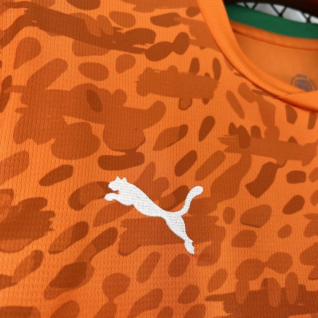 Leazofoot Côte d'Ivoire 2026 home jersey in orange with a textured animal print pattern and white Puma logo.