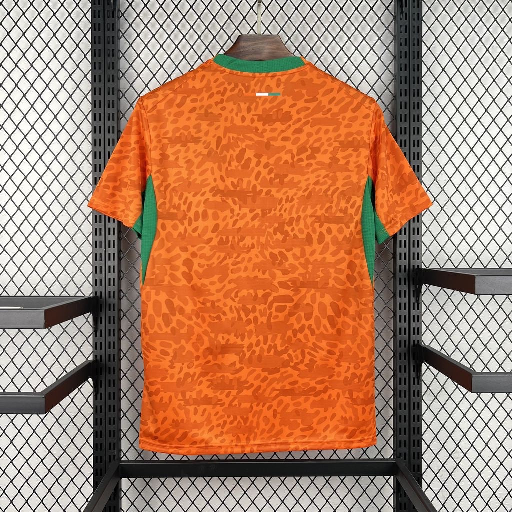 Leazofoot Côte d'Ivoire 2026 home football jersey in orange with a subtle leopard print pattern and green accents.