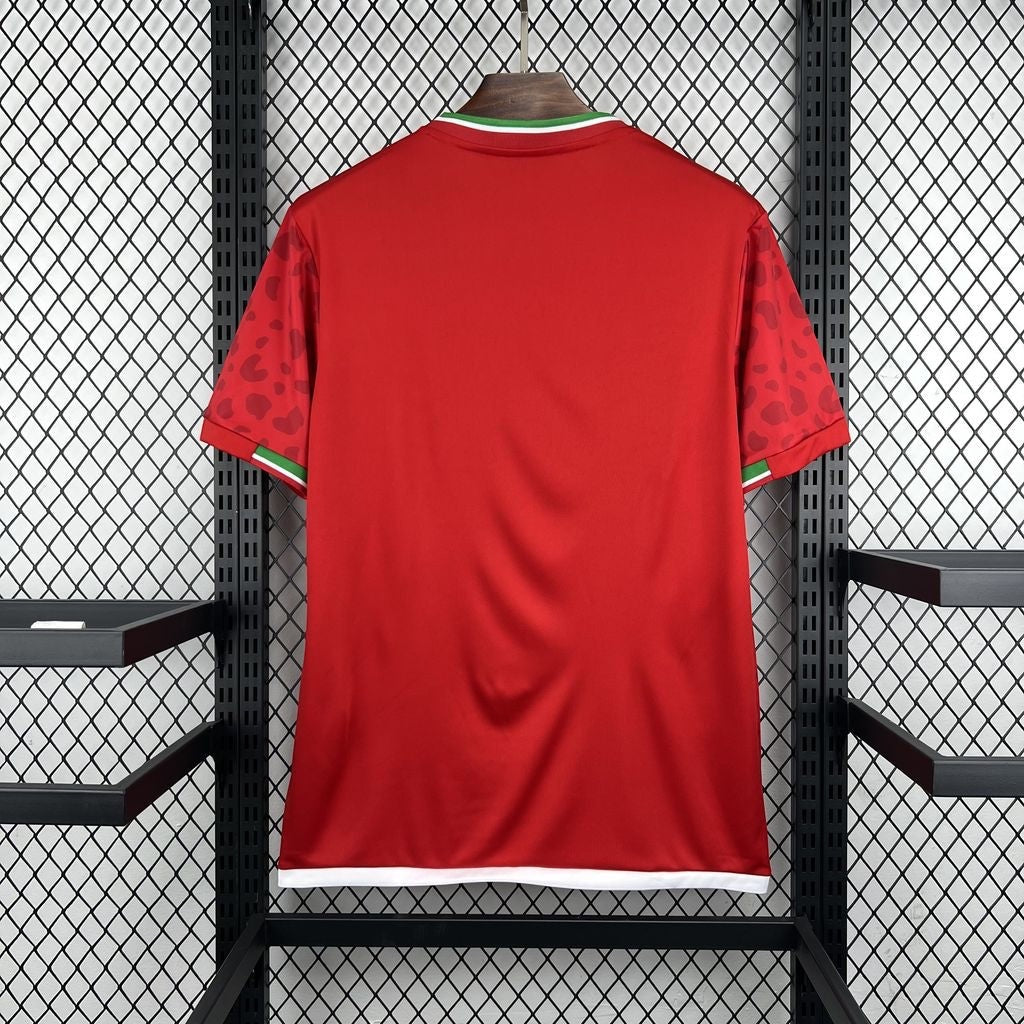 Leazofoot Iran 2026 away soccer jersey in red with green and white trim and patterned sleeves on a display rack.