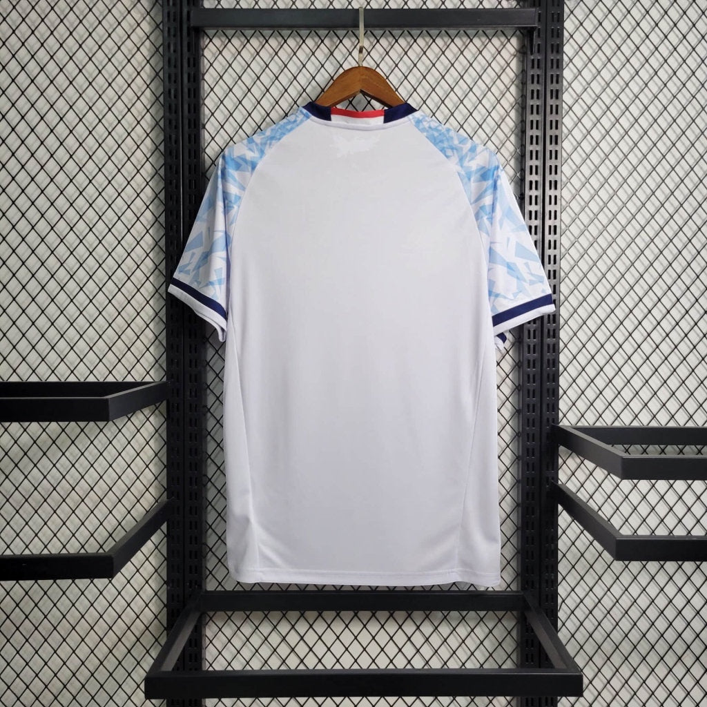 Back view of Leazofoot Japan 2023 football jersey featuring a white body and light blue patterned sleeves on a hanger.