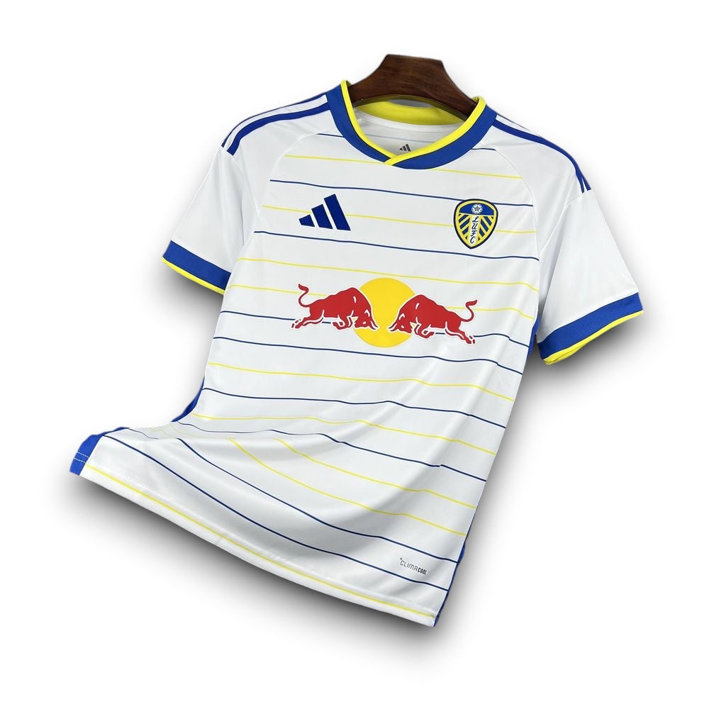 Leazofoot Leeds United 26/27 home jersey in white with blue and yellow stripes, Red Bull sponsor, and club crest.