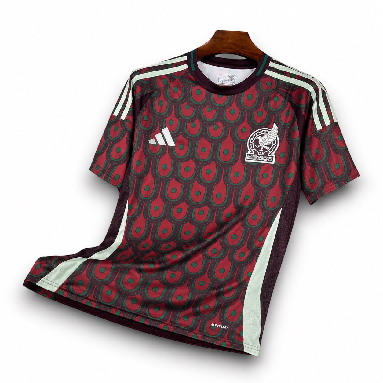 Leazofoot 2024 Mexico home soccer jersey in maroon and green with a unique feather-inspired pattern on a hanger.