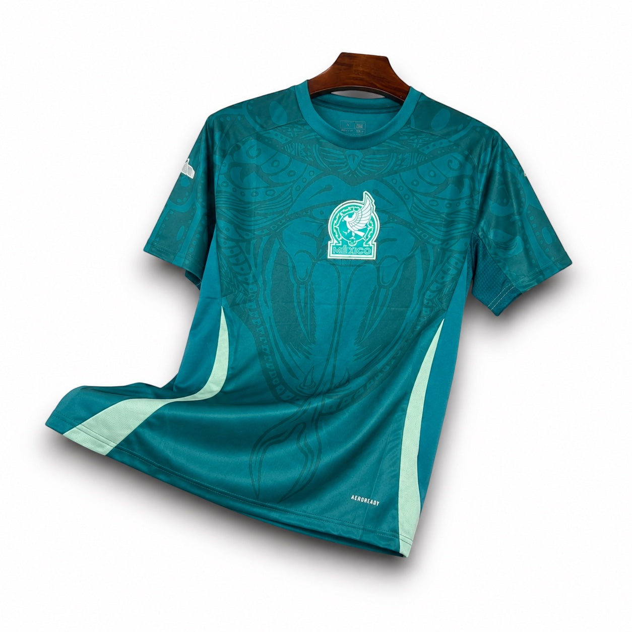 Leazofoot Mexico 2024 pre-match jersey in teal with intricate graphic patterns and team crest on a wooden hanger.
