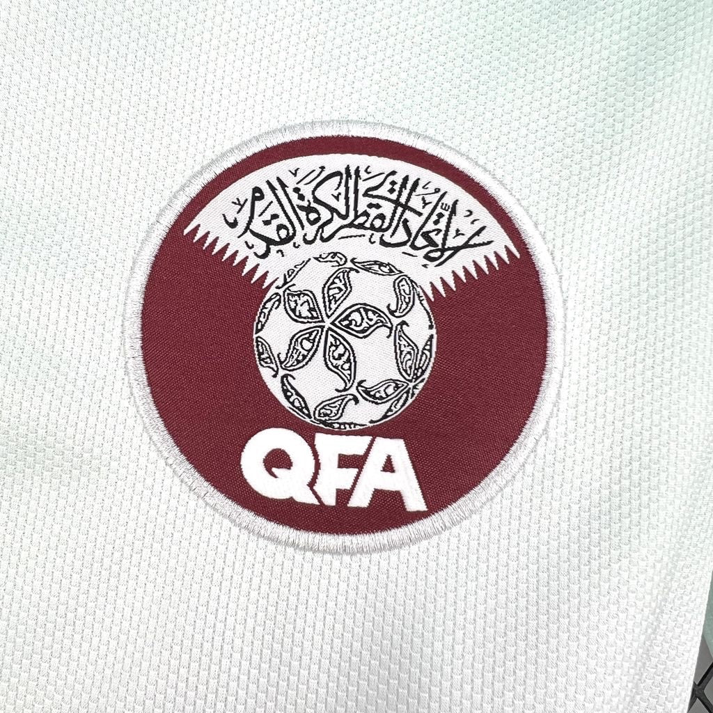 Leazofoot Qatar 2026 away jersey featuring the embroidered QFA crest on a white textured performance fabric.