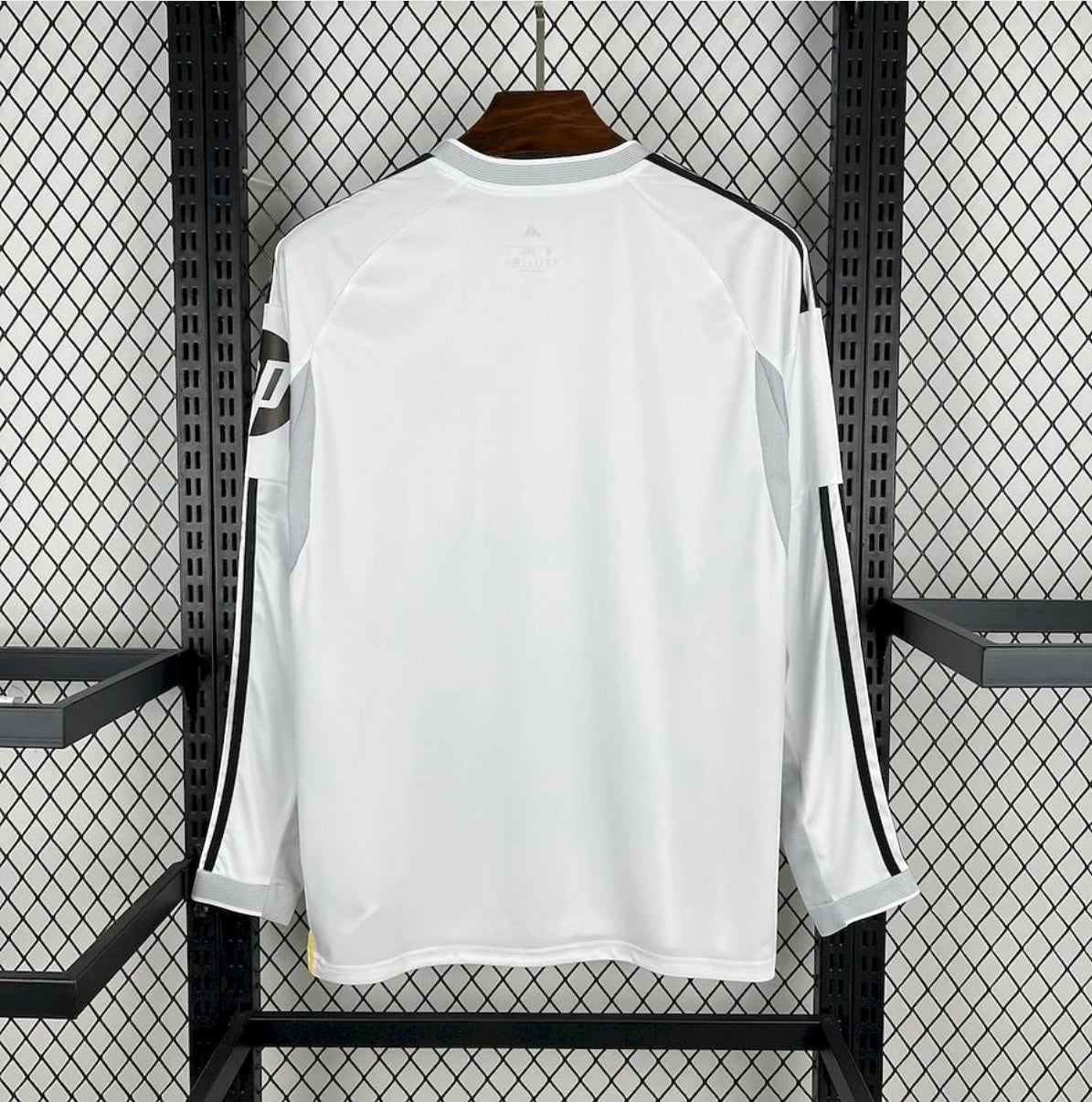 Leazofoot Real Madrid 25/26 long-sleeve home jersey in white with black shoulder stripes, back view on hanger.
