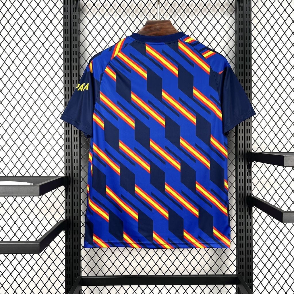Leazofoot Spain 2026 pre-match football jersey with a blue base and a geometric pattern of navy, red, and yellow stripes.