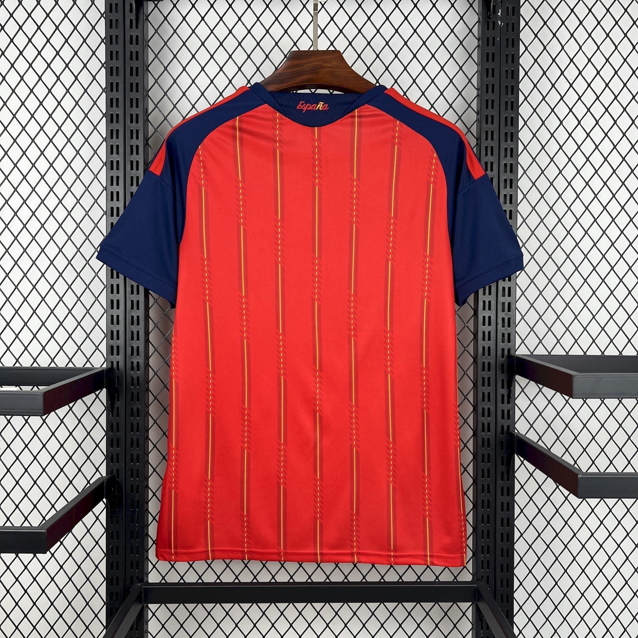 Leazofoot Spain 2026 home soccer jersey. Red with vertical yellow and darker red stripes, navy blue sleeves and collar.
