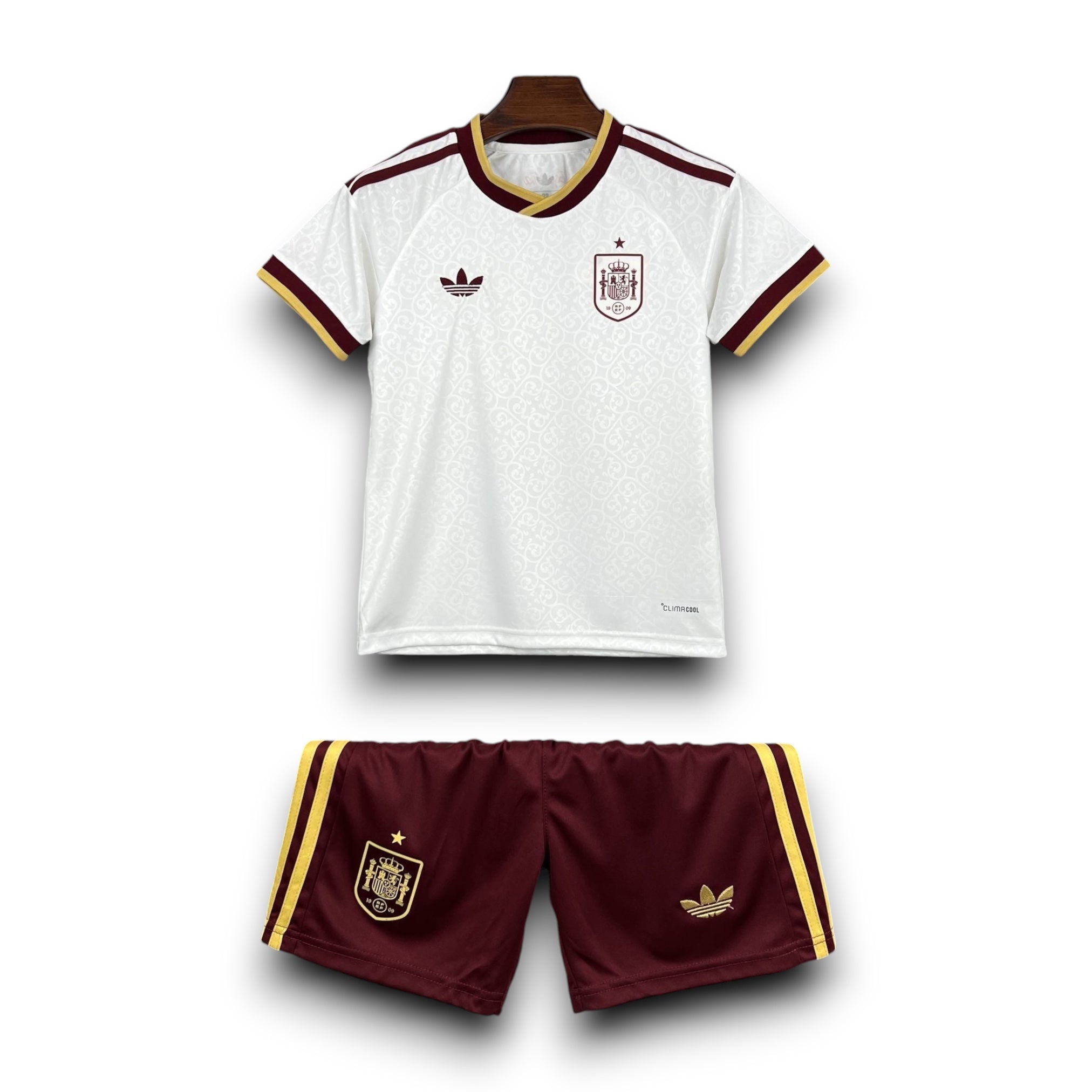 Leazofoot Spain kids' football kit: white jersey with maroon and gold trim, maroon shorts with gold trim. Features Spain crest and Adidas logo.